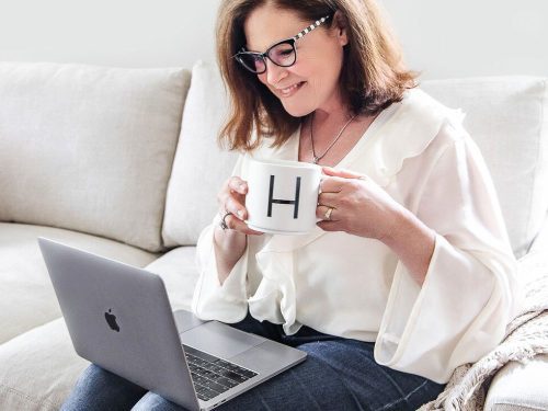 Ginger Harrington sits on sofa blogging about deeper life with God on laptop.
