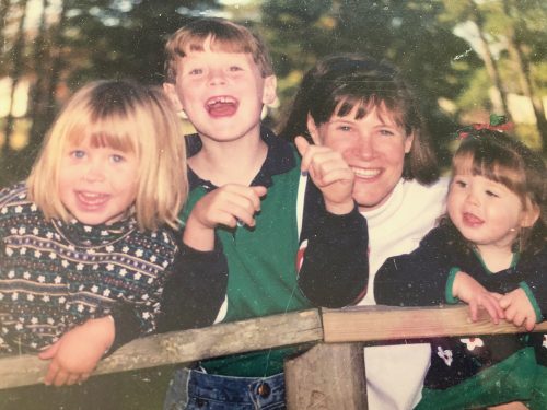 a mom with three young children smile at camera for post on encouraging moms