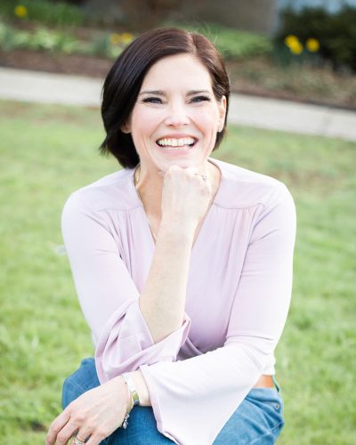 Author Christine Trimpe is smiling at the cameral wearing a pink blouse and jeans.